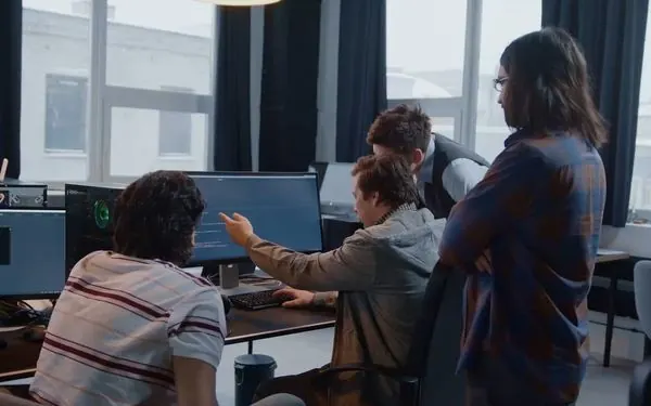 Time reunido em volta de uma mesa com notebooks